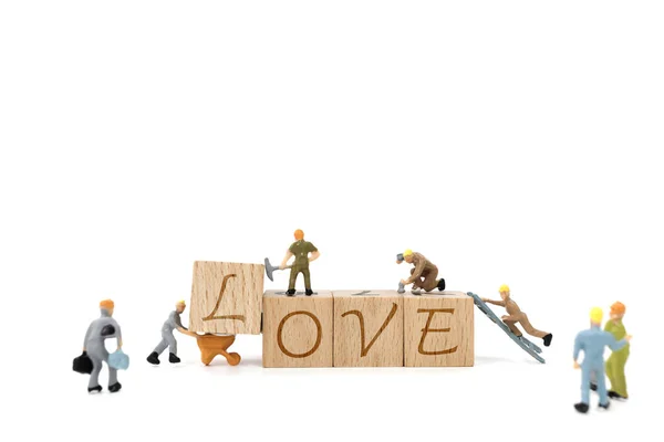 Miniatuur werknemer teambuilding woord liefde op witte achtergrond — Stockfoto