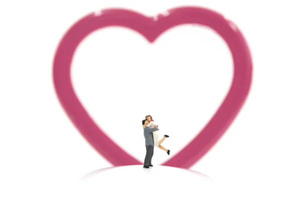 Miniature couple hugging and red heart on white background