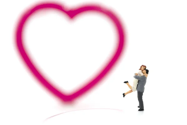 Miniature couple hugging and red heart on white background