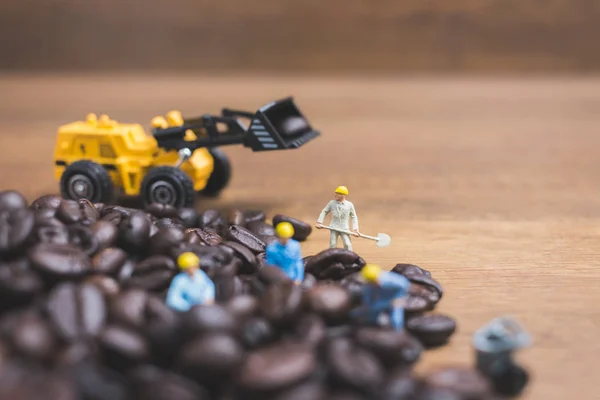 Personas en miniatura trabajando en granos de café tostados — Foto de Stock