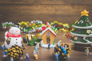 Noel dekorasyonları ahşap bir arka plan üzerinde oluşturma minyatür insanlarla yaratıcı kavramı. 