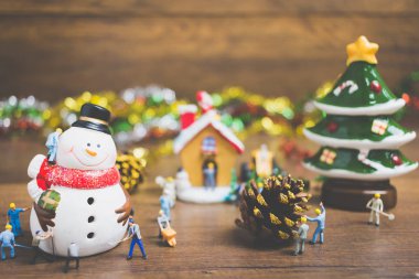 Noel dekorasyonları ahşap bir arka plan üzerinde oluşturma minyatür insanlarla yaratıcı kavramı. 