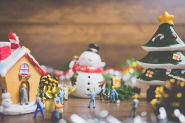 Noel dekorasyonları ahşap bir arka plan üzerinde oluşturma minyatür insanlarla yaratıcı kavramı. 