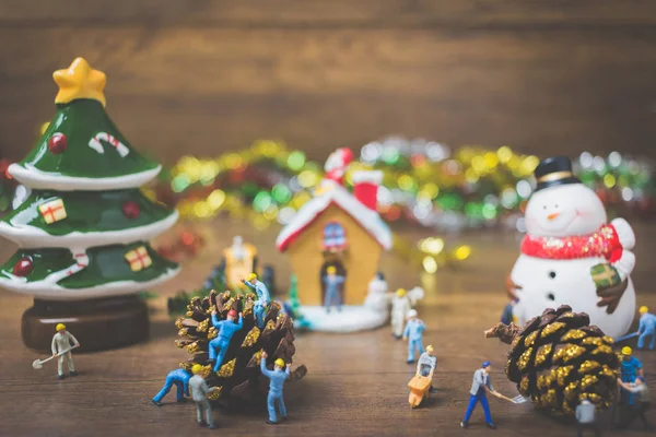 Noel dekorasyonları ahşap bir arka plan üzerinde oluşturma minyatür insanlarla yaratıcı kavramı. 