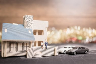 Sikke para ile ev ile oturan minyatür insanlar. 