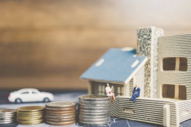 Sikke para ile ev ile oturan minyatür insanlar. 