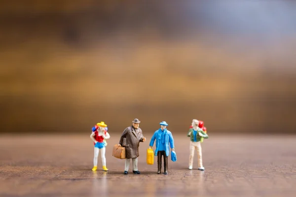 Miniatuur mensen reizigers permanent op houten achtergrond — Stockfoto