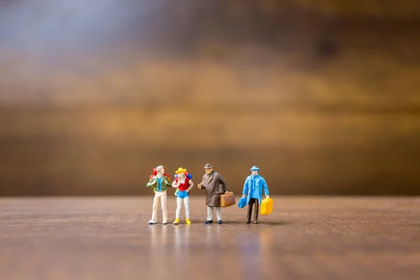 Miniatuur mensen reizigers permanent op houten achtergrond — Stockfoto