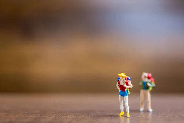 Personas en miniatura viajeros de pie sobre fondo de madera — Foto de Stock