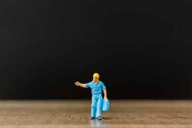 Minyatür insanlar çalışan siyah arka plan ile ahşap zemin üzerinde 