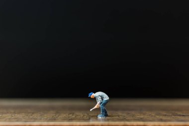 Minyatür insanlar çalışan siyah arka plan ile ahşap zemin üzerinde 