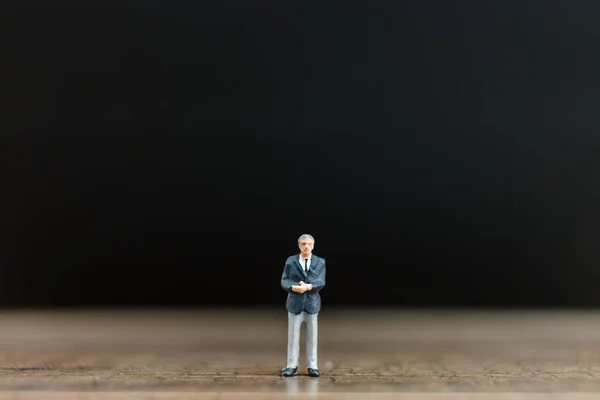 Personas en miniatura hombre de negocios en piso de madera con fondo negro — Foto de Stock