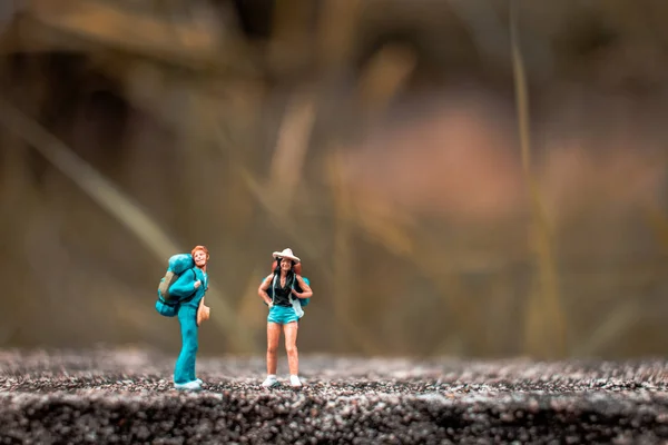 Mochileiro em miniatura em pé na parede de concreto — Fotografia de Stock