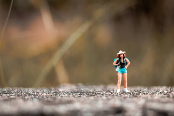 Mochileiro em miniatura em pé na parede de concreto — Fotografia de Stock