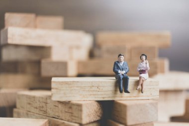 Minyatür insanlar: ahşap blokta oturan iş adamları