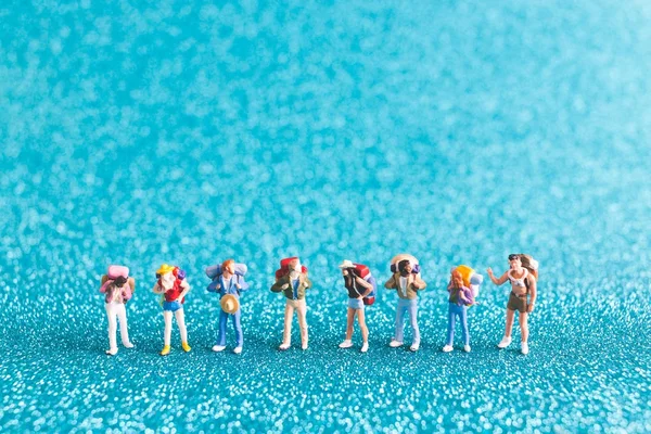 Miniatur-Backpacker, Touristen auf blauem Glitzerhintergrund — Stockfoto