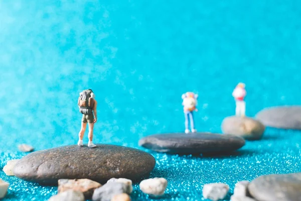 Mochileiro em miniatura, Pessoas turísticas sobre fundo brilho azul — Fotografia de Stock