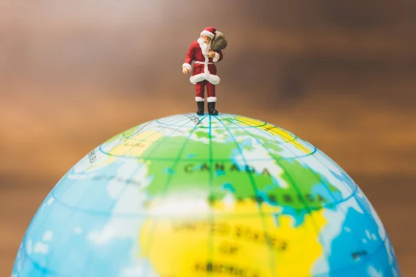 Personnes miniatures : Père Noël portant sur le globe — Photo