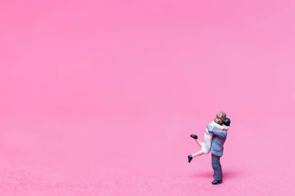 Miniatur-Paar umarmt auf rosa Hintergrund — Stockfoto