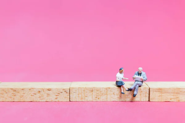 Miniaturmenschen: Paar sitzt auf Holzklotz — Stockfoto