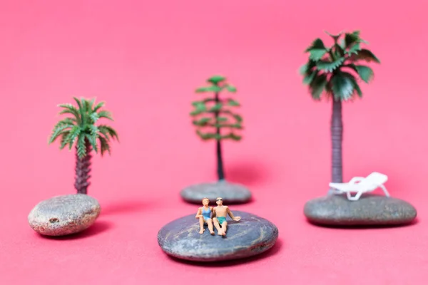 Miniature people wearing swimsuit relaxing on the rock — Stock Photo, Image