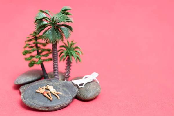 Miniaturmenschen im Badeanzug relaxen auf dem Felsen — Stockfoto