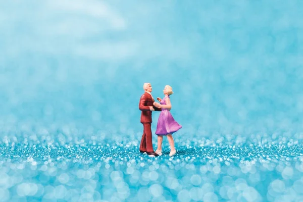 Miniaturmenschen, Paar tanzt auf blauem Glitzerhintergrund — Stockfoto