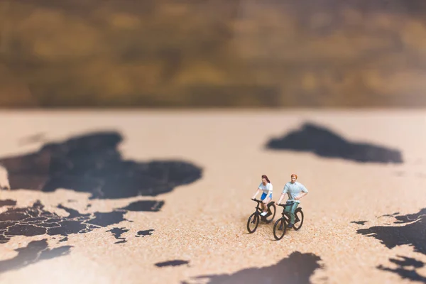 Miniaturmenschen auf dem Fahrrad auf der Weltkarte — Stockfoto