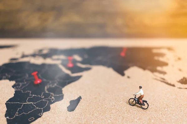 Dünya Haritası üzerinde Bisiklete binmek minyatür insanlar yolcuları — Stok fotoğraf