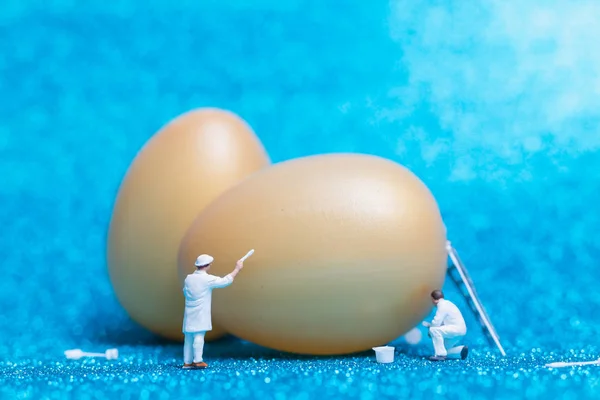 Miniature people :Painter is painting Easter-eggs for Easter day