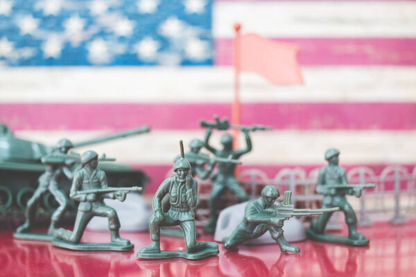 Miniature toy soldiers in battle scene with american flag background