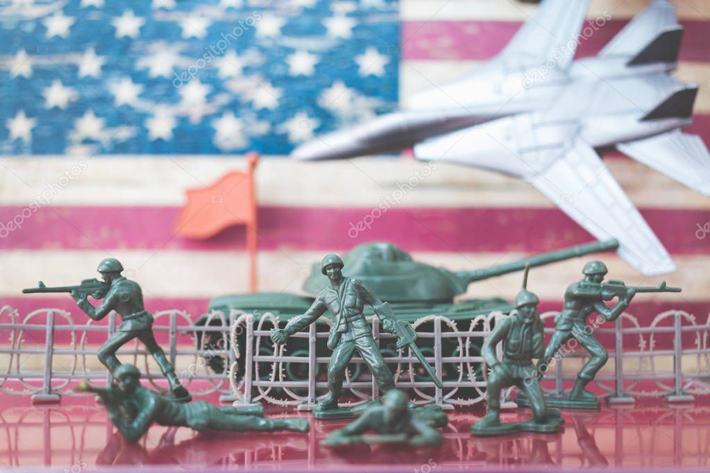 Miniature toy soldiers in battle scene with american flag background