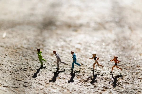 Miniatyr människor: Grupp människor kör på betonggolv — Stockfoto
