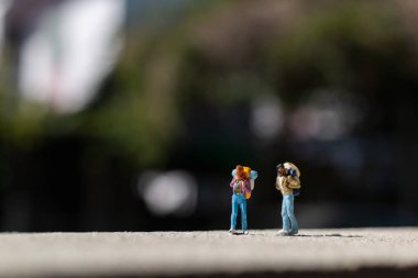 Minyatür insanlar: Sırt çantalı gezgin yolda duruyor