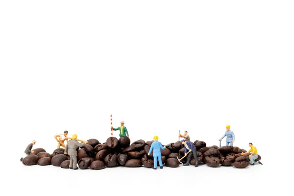 Personas en miniatura trabajando con granos de café tostados sobre fondo blanco — Foto de Stock