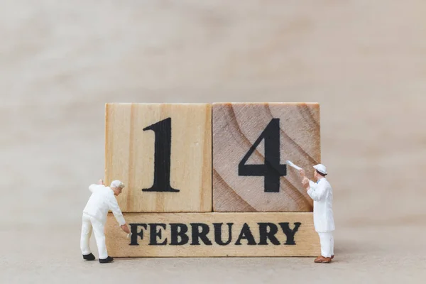 Miniature people painting wooden block 14 FEB on wooden background, happy valentines day concept