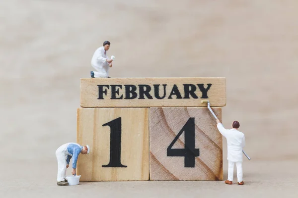 Miniature people painting wooden block 14 FEB on wooden background, happy valentines day concept