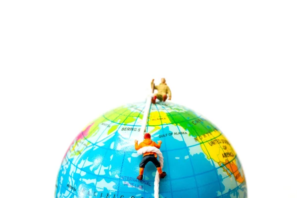 Miniature people: Hikers climbing up on the Globe — Stock Photo, Image
