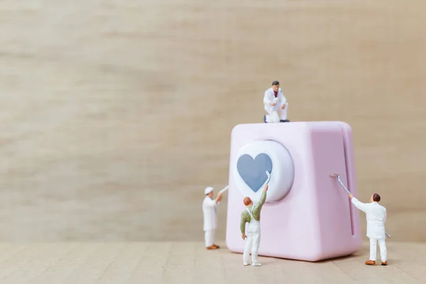 Miniature people painting Heart shaped punching machine with copy spaces for your text