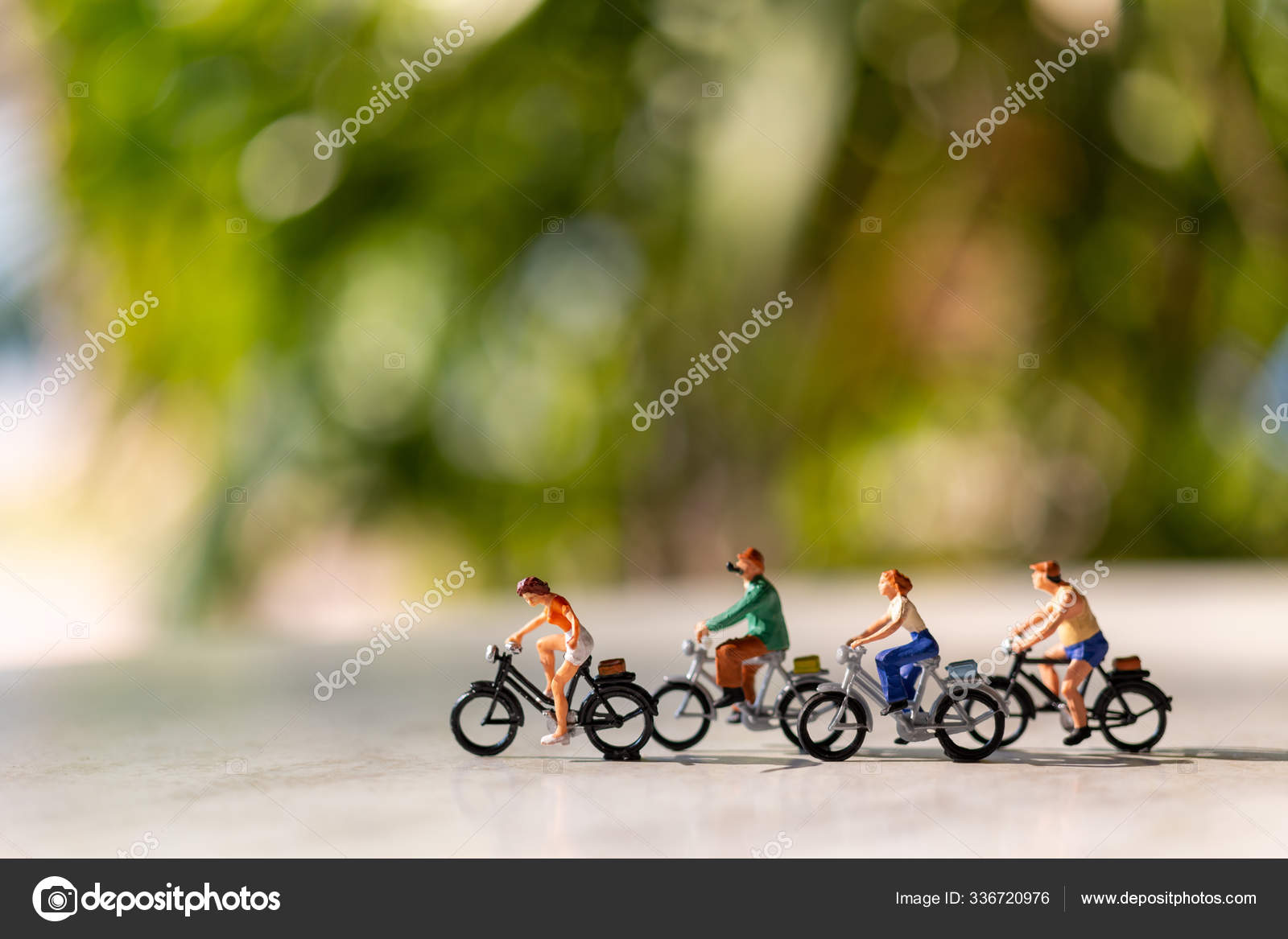 Miniature people ride a bicycle outdoors with green bokeh background Stock  Photo by ©sirichaiDeposit 336720976