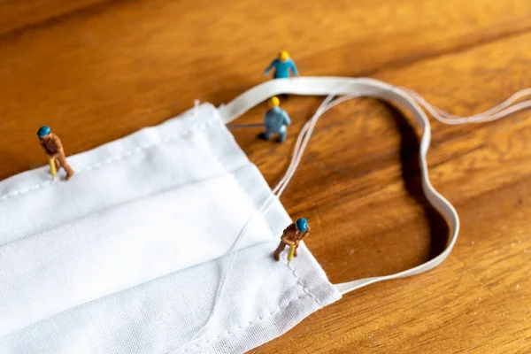 Miniaturmenschen Arbeiterteam Bastelt Aus Weißem Stoff Eine Hausgemachte Maske Auf — Stockfoto
