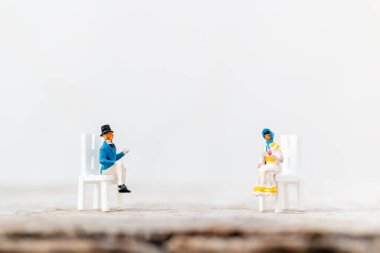 Minyatür insanlar COVID-19 koronavirüs salgınından korunmak için sosyal mesafeyi korumak için selamlıyorlar.