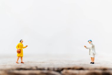 Minyatür insanlar COVID-19 koronavirüs salgınından korunmak için sosyal mesafeyi korumak için selamlıyorlar.