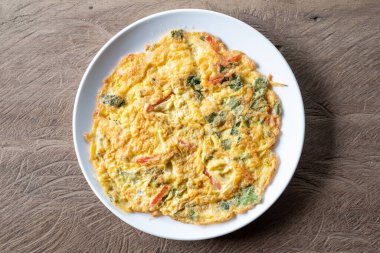 Tahta masada servis edilen yeşil çay yapraklı omlet manzarası..