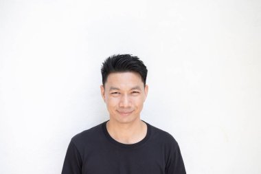 Beyaz duvar arkasında duran Asyalı genç adamın portresi