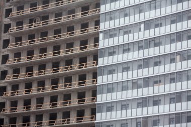 İnşaat. Binanın arka planı, evin yarısı bitmiş, yarısı bitmemiş. Kavramsal bina fotoğrafı. Cam cepheli modern bir konut inşaatı.