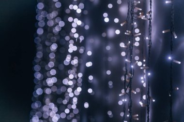 Çelenk, neşeli ışıklar. Şenlikli ışıklandırma. Siyah arka planda parlak bir çelenk, seçici bir odak. LED çelenk, kopyalama alanı olan şenlikli arkaplan.