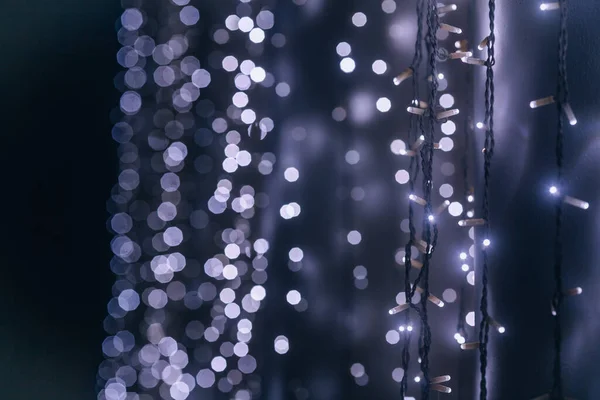 Garland, joyful lights. Festive lighting. Bright garland on a black background, selective focus. LED garland, festive background with copy space.