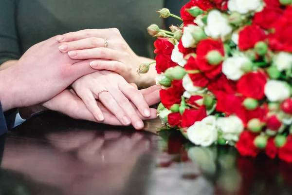 Руки з обручкою на тлі букета троянд — стокове фото