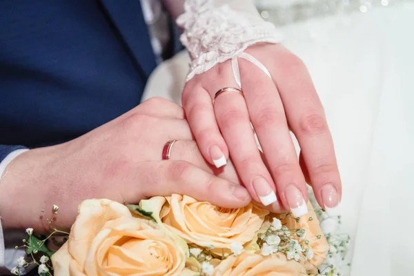 Руки з обручками на весільний букет — стокове фото